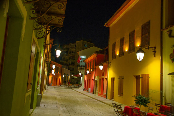 VLORA / VLORE, ALBANIA: Straat met oude historische gebouwen in het centrum 's nachts. Straatverlichting brandt op de huizen.. - Foto, afbeelding