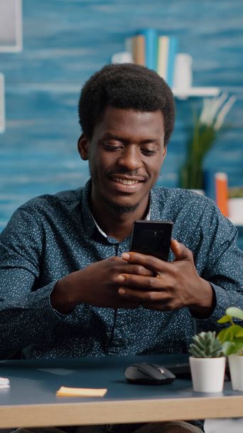 Black man in living room enjoying social media content on phone - Фото, зображення