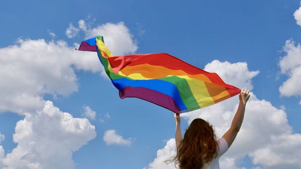 Henkilö, jolla on LGBT-lippu taivaalla - Valokuva, kuva