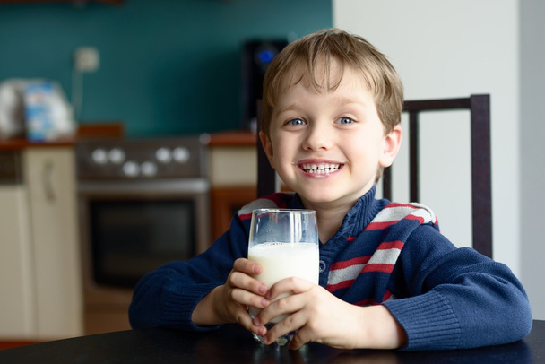 Улыбающийся мальчик держит здоровый стакан свежего молока
 - Фото, изображение