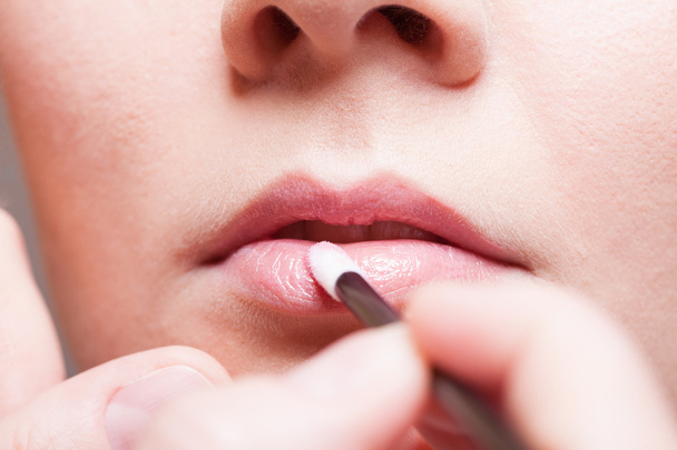 Girl applying lipgloss lipstick on lips. - Fotó, kép