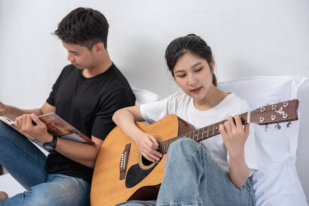 Жінка сидить грати на гітарі і чоловік тримає книгу і співає
. - Фото, зображення