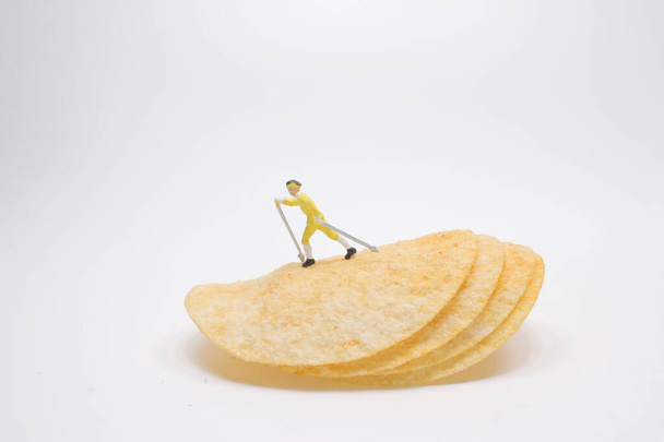 a mini skier sliding down the stack of potato chips - Fotografie, Obrázek