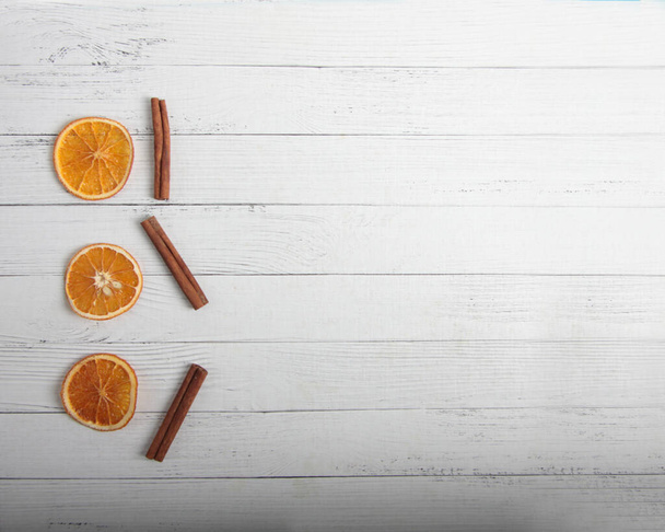 Christmas backgrond - dried orange slices and cinnamon sticks on white wooden background flat lay. Image contains copy space - Photo, Image