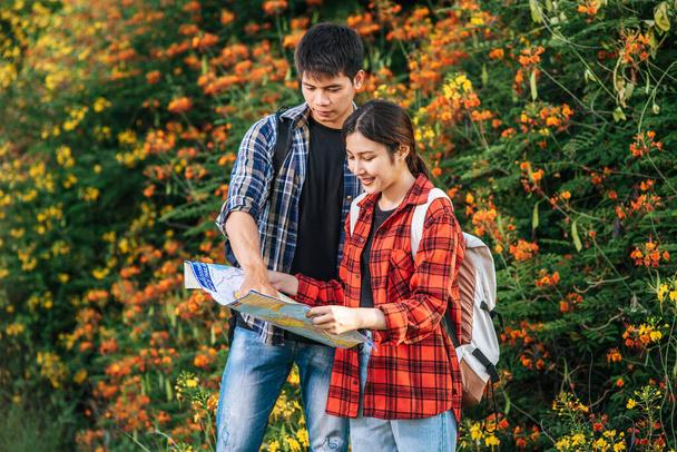 Toeristen mannen en vrouwen kijken naar de kaart bij de bloementuinen. - Foto, afbeelding