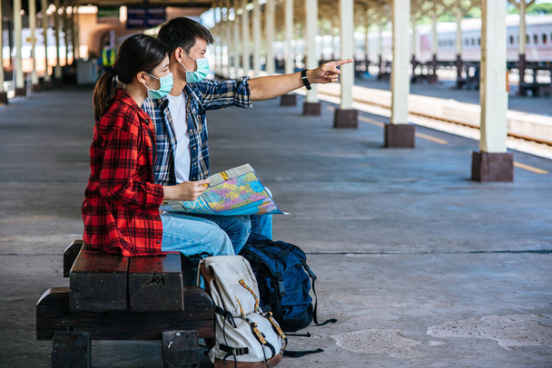 Male and female tourists look at the map beside the railway. - Foto, Bild