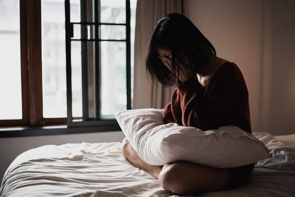 Depressive Frau sitzt auf dem Bett im Schlafzimmer - Foto, Bild