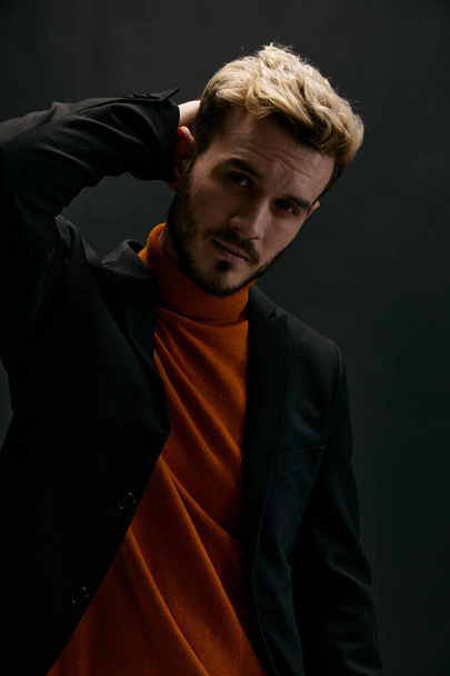 portrait of a handsome man in a jacket and an orange sweater gesturing with his hands - Fotoğraf, Görsel