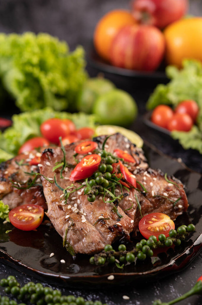 Krájený vepřový steak s bílým sezamem a čerstvými paprikovými semínky a rajčaty, citróny, chilli a salátem. - Fotografie, Obrázek