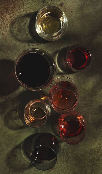 赤、緑の背景に錆びたガラスの中でバラと白のワイン、トップビュー。ワインバー、ショップ、ワイナリー、ワインの試飲コンセプト。強い光と厳しい影 - 写真・画像