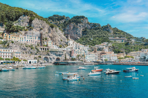 Krajobraz z Amalfi miasta na słynnym wybrzeżu amalfi, Włochy. Wybrzeże Amalfi jest najbardziej popularnym miejscem podróży i wypoczynku w Europie. Włoski letni raj. Góry na wybrzeżu Amalfitany. Wioska z małą plażą i kolorowe domy położone na skale - Zdjęcie, obraz