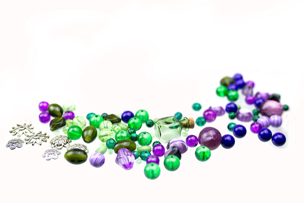 Perles vertes et violettes, fils à coudre et autres fournisseurs de bijoux isolés sur un fond blanc. Concentration sélective. Gros plan. - Photo, image