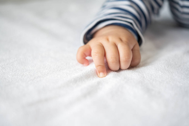 Newborn baby hand in white bed. Selective focus. - Фото, изображение