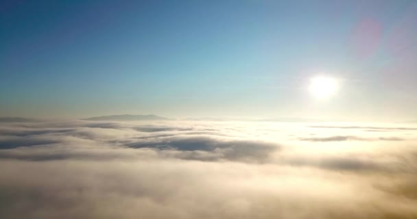 Foto aérea de majestuoso amanecer en las montañas. Valle entre las montañas está cubierto de niebla y está iluminado por los cálidos rayos del sol naciente. Montañas cubiertas de bosque natural. - Metraje, vídeo
