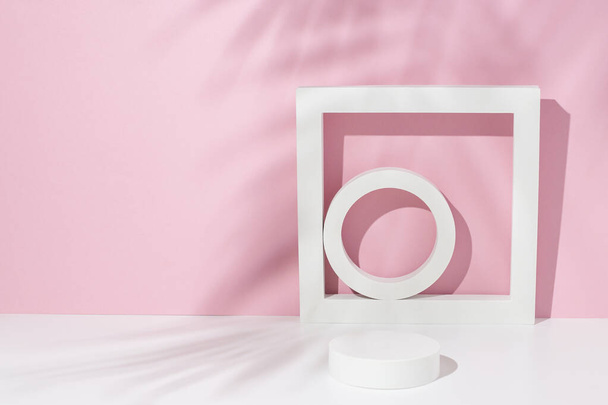 Podium white square, circles for presentation under the shadow of palm leaves on a white pink background. - Foto, afbeelding