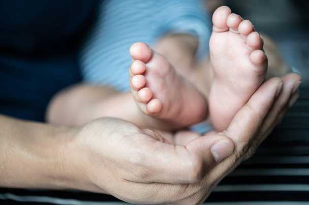 The mother's hand graced the feet of the newborn. - Фото, изображение