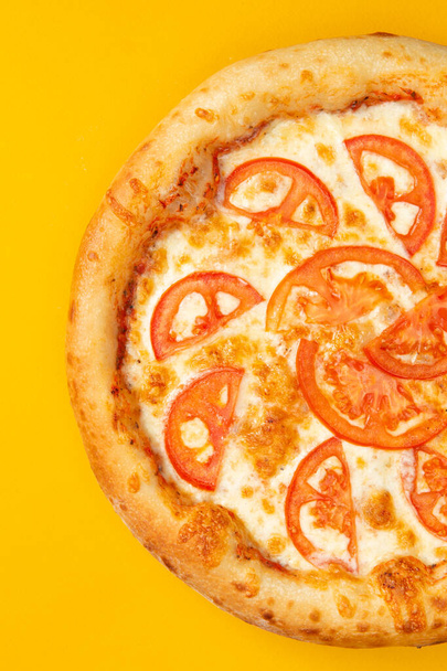 Пицца с сыром и томатными ломтиками на желтом фоне. Селективный фокус - Фото, изображение