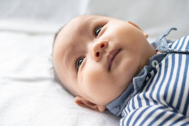 Ένα νεογέννητο μωρό που ανοίγει τα μάτια του και κοιτάζει στο πλάι - Φωτογραφία, εικόνα