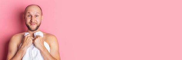 Mladý vousatý nahý muž pokrytý ručníkem na růžovém pozadí. Nápis. - Fotografie, Obrázek
