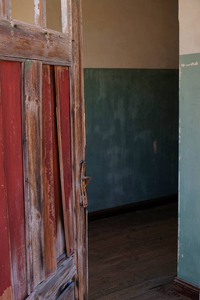 Az ajtó félig nyitva van egy házban Kolmanskop szellemvárosában, Namíbiában. Részlet - Fotó, kép