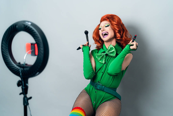 Happy drag queen influenciador social vlogging on-line uma classe de maquiagem com câmera de smartphone e anel levou - Foto, Imagem