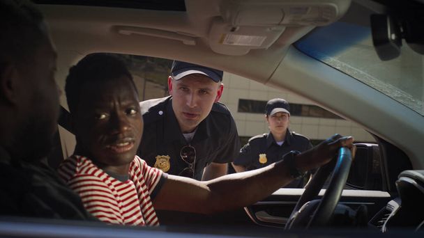 Серйозний поліцейський перевіряє чорних чоловіків у машині
 - Фото, зображення