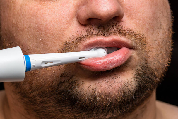 Κοντινό πλάνο του ανθρώπου που βουρτσίζει τα δόντια του με ηλεκτρική οδοντόβουρτσα - Φωτογραφία, εικόνα