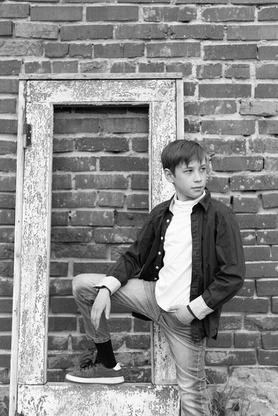 Модно одетый парень в рубашке стоит на фоне старой разрушенной кирпичной стены. Крупный план. Выборочный фокус. Портрет - Фото, изображение