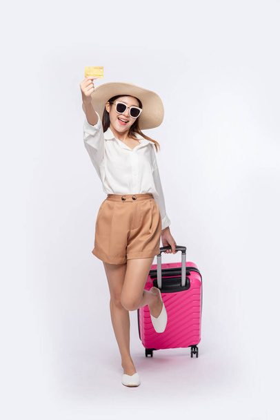 Girl wearing a hat holding credit card and suitcase to travel. - Photo, Image