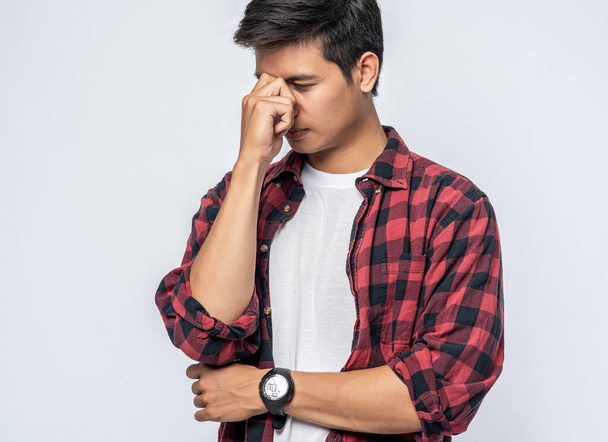 Ein Mann mit Migräne, der ihre Hand in der Nase hält - Foto, Bild