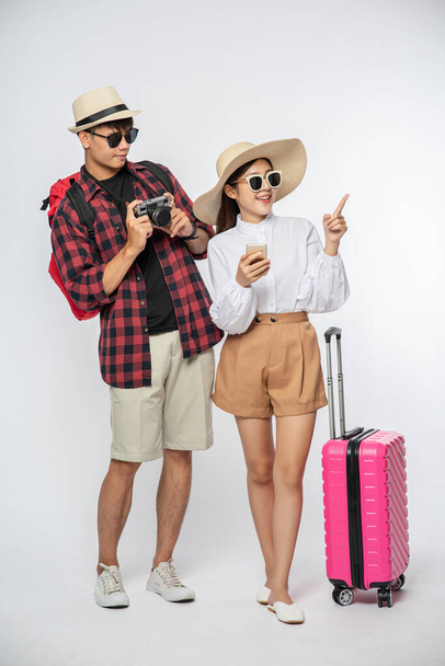 Men and women dressed to travel, wear glasses, and take pictures. - Foto, immagini