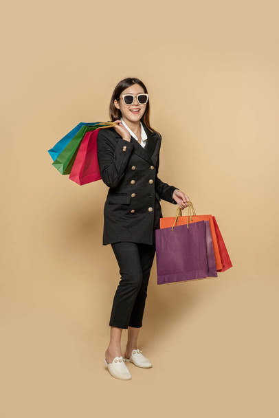 The woman wore black clothes and glasses, along with many bags, to go shopping. - Foto, imagen