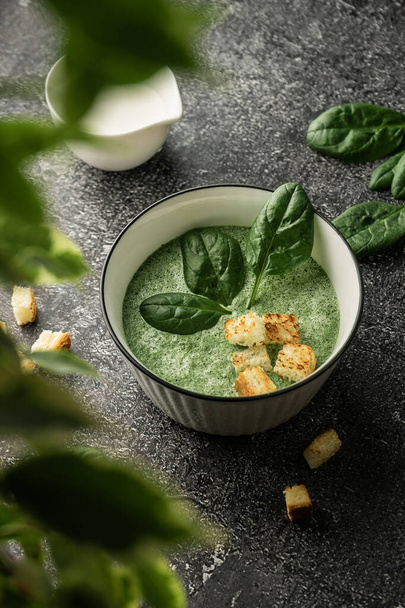 cream soup of green fresh spinach with cream and croutons for decoration. on a dark copyspace background, For menus and articles with recipes - Foto, imagen
