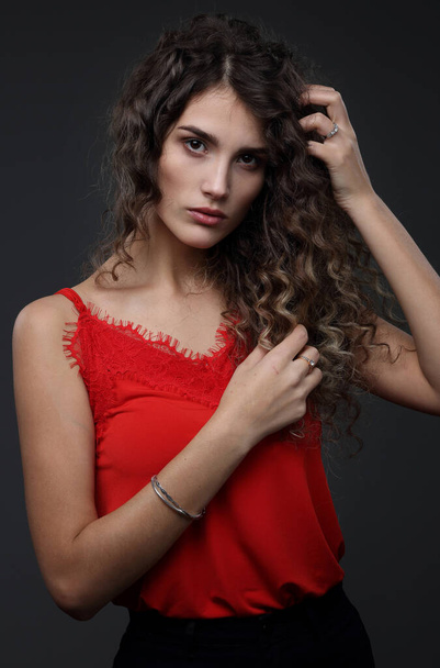Beautiful girl with highlighted hair in a red blouse on a dark background - Foto, imagen