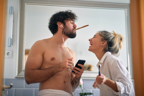 beautiful young adult caucasian couple having fun in the morning, singing, brushing teeth in the bathroom. - Photo, image