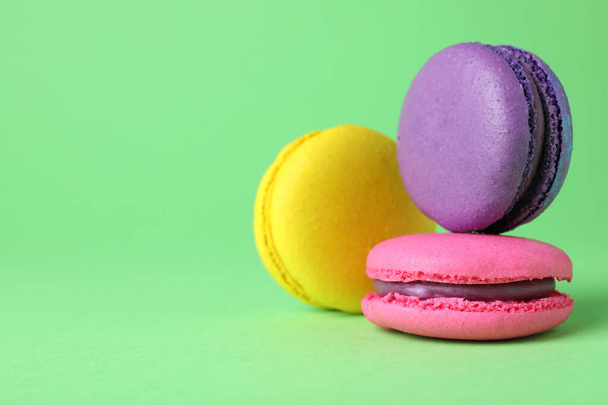 Delicious colorful macarons on green background, closeup. Space for text - Foto, Bild