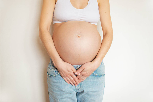Беременная женщина с болью в животе. Он держит живот руками от боли. Болезнь во время беременности. - Фото, изображение