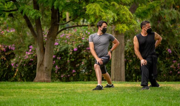 Männer im Park mit Masken beim Sport, Yoga und Stretching - Foto, Bild