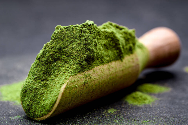 Green tea, matcha. Powdered young barley or wheat grass on wooden scoop. Detox superfood concept. - Фото, зображення
