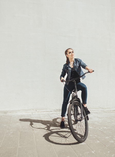 Young woman hipster standing with black bike - Fotó, kép