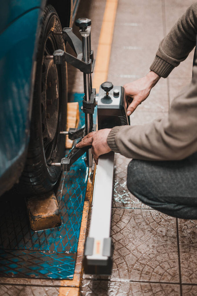 Close-up de um pneu preso por um nivelador que passa o alinhamento automático das rodas na garagem, garagem e ferramentas para o mecânico. novo - Foto, Imagem