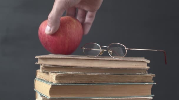 Τοποθέτηση ενός ώριμου μήλου σε βιβλία με γυαλιά ως σημάδι της εκπαίδευσης. Μάθηση και γνώση έννοια βίντεο. - Πλάνα, βίντεο