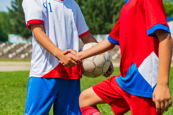 A close-up of the cut off arms of two young footballers. Handshake before the start of the match. - Foto, afbeelding
