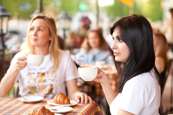 Smiling brunette woman at cafe drinking coffee with friends. Communication and friendship concept. - Foto, Imagen