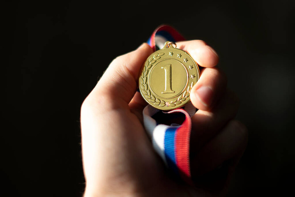 mano de los campions sosteniendo una medalla de oro, concepto de suerte ganador simple - Foto, Imagen