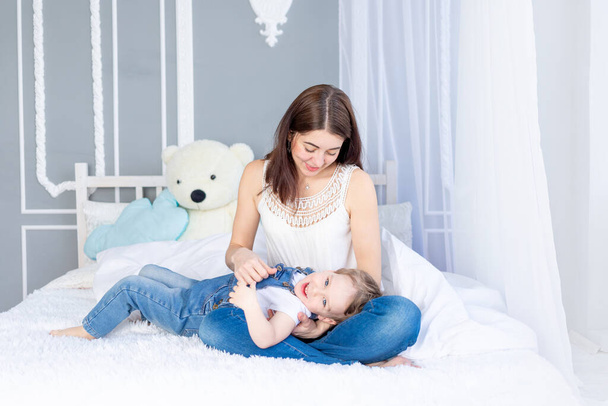 A happy, loving family. Mom and baby son play at home on the bed, have fun and laugh - Zdjęcie, obraz
