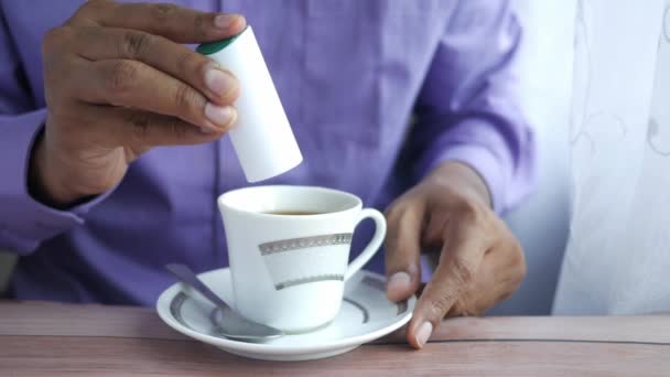 fiatalember tesz mesterséges édesítőszert egy csésze teát az asztalon . - Felvétel, videó
