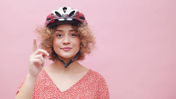 Όμορφη νεαρή κοπέλα φορώντας ένα κράνος ποδηλάτου - δείχνοντας ένα δάχτυλο - Φωτογραφία, εικόνα
