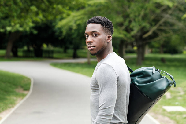 Formda genç bir zenci spor çantasıyla antrenmana gidiyor. O bir parkta.. - Fotoğraf, Görsel