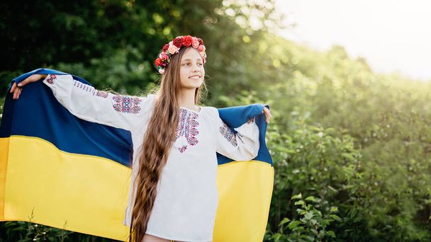 Ukraine's Independence anniversary Day. Constitution day. Ukrainian child girl in embroidered shirt vyshyvanka with yellow and blue flag of Ukraine in field. Kyiv, Kiev day - Photo, Image